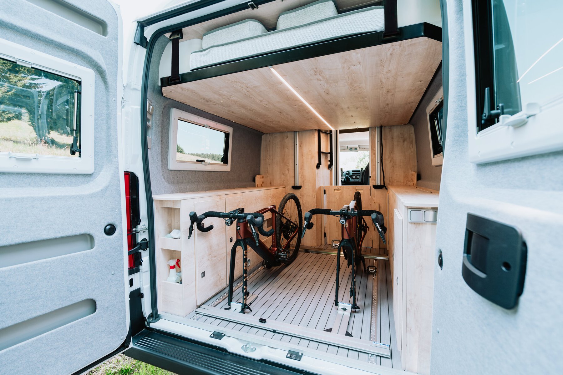 Geöffnete Hecktüren: Zwei Gravelbikes finden bequem in der Heckgarage Platz, darüber das Hubbett